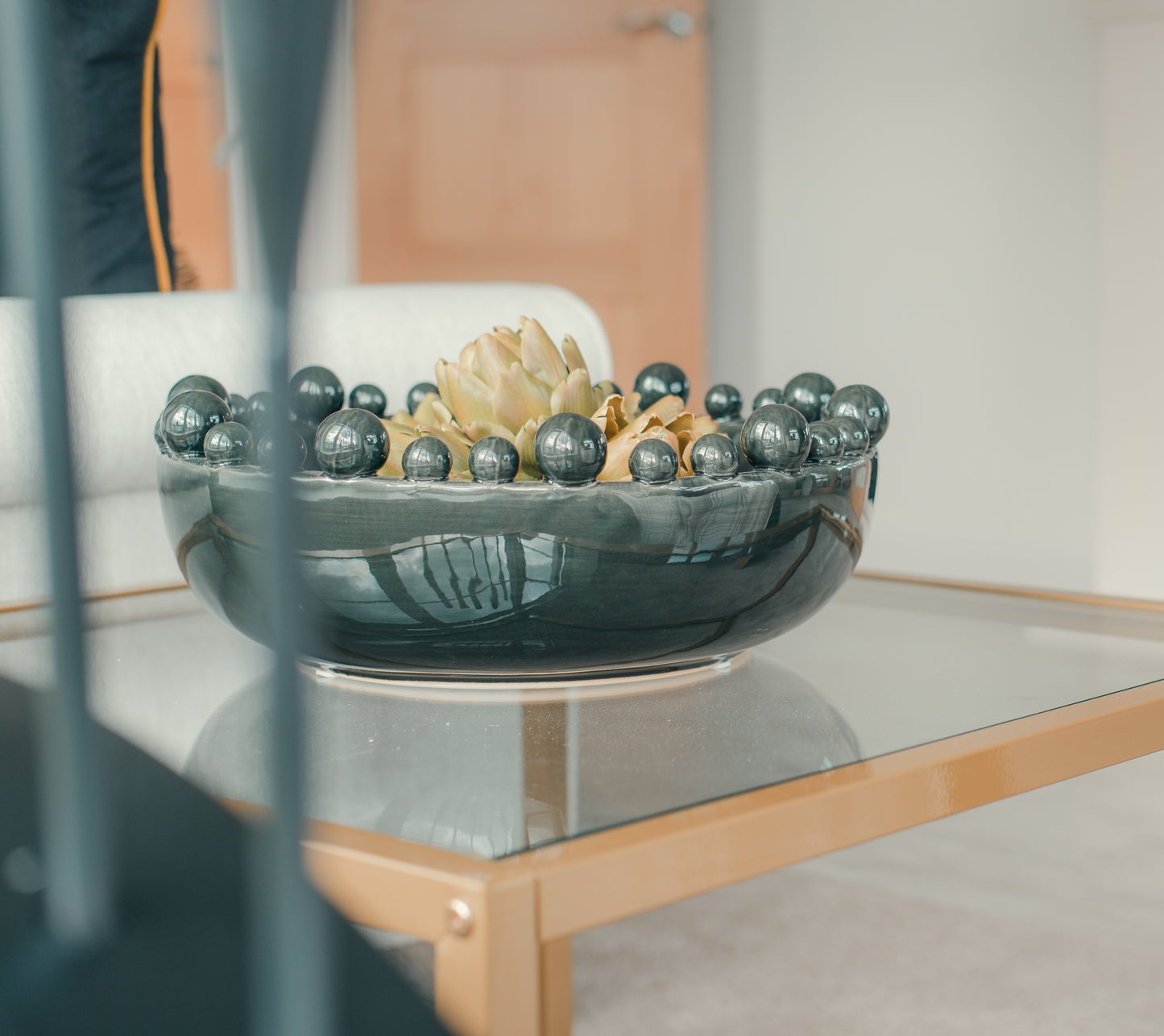 Decorative bowl with Faux Green Artichoke Head on a glass table