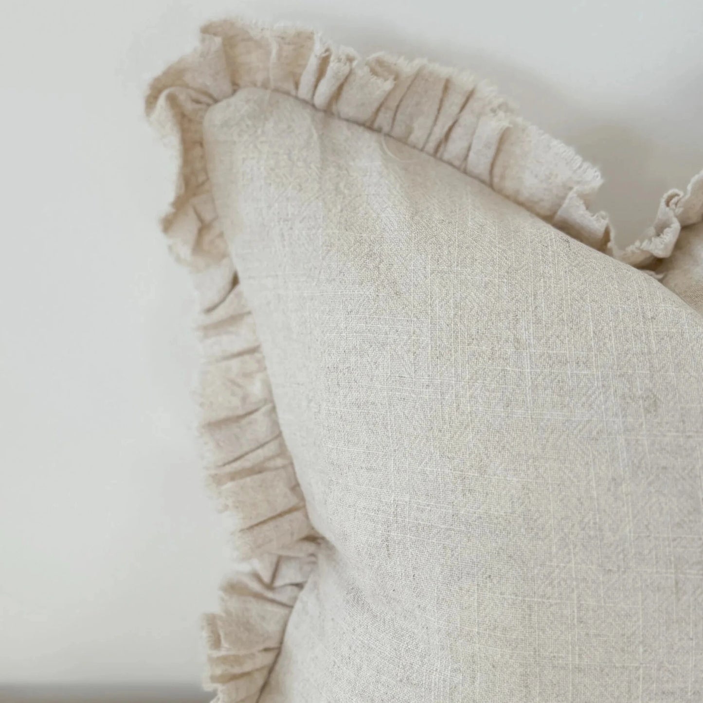 Textured pillow with ruffled edge against a plain background