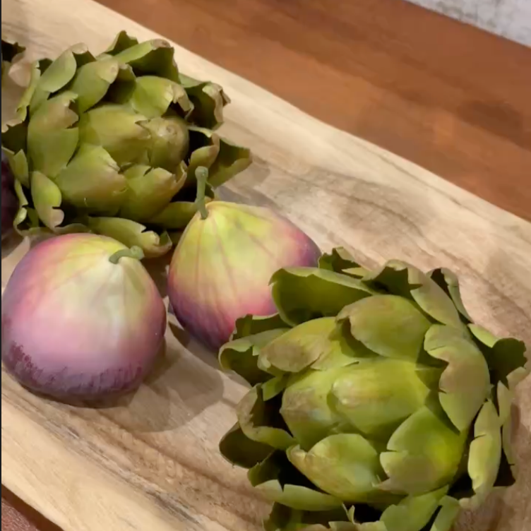Artichokes on a wooden surface with a neutral background