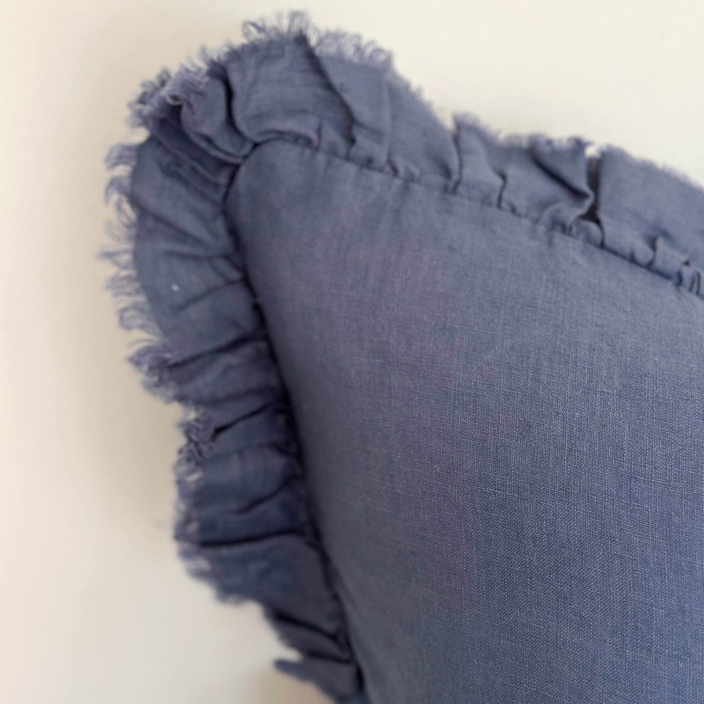Blue pillow with ruffled edge on a light background