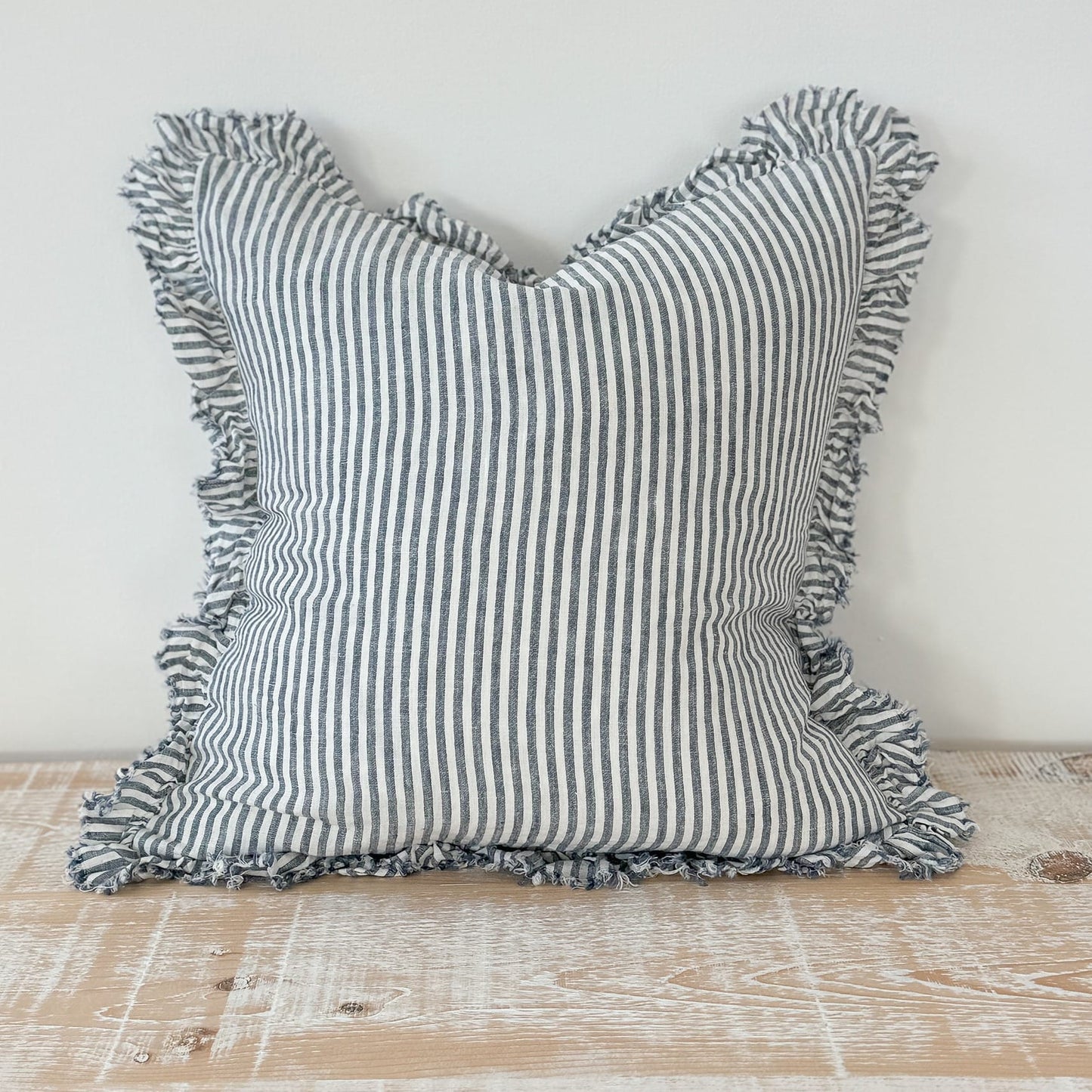 Striped pillow with ruffled edges on a wooden surface