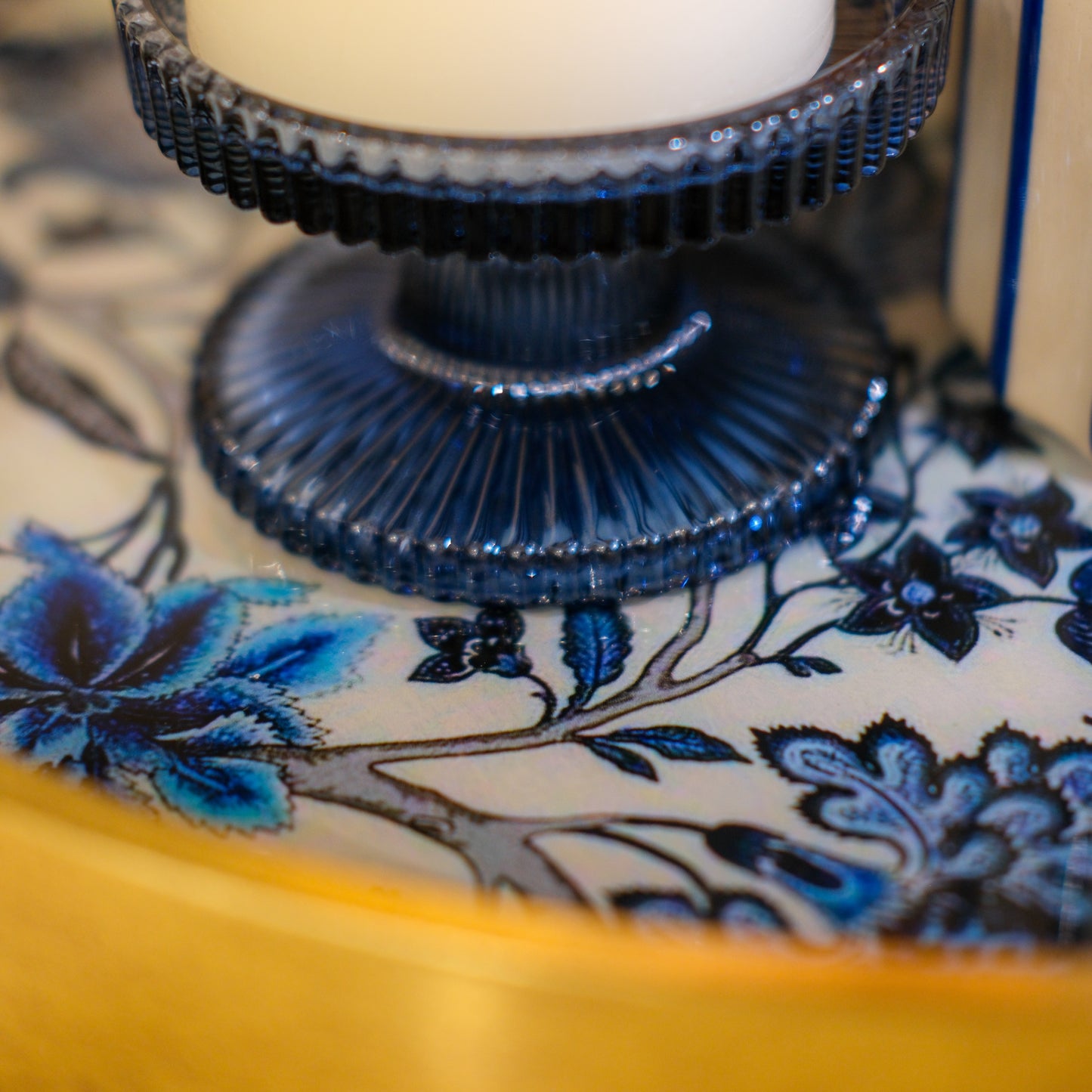 Decorative blue candle holder on a floral-patterned surface