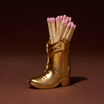 Gold boot-shaped matchbox with matches on a brown background
