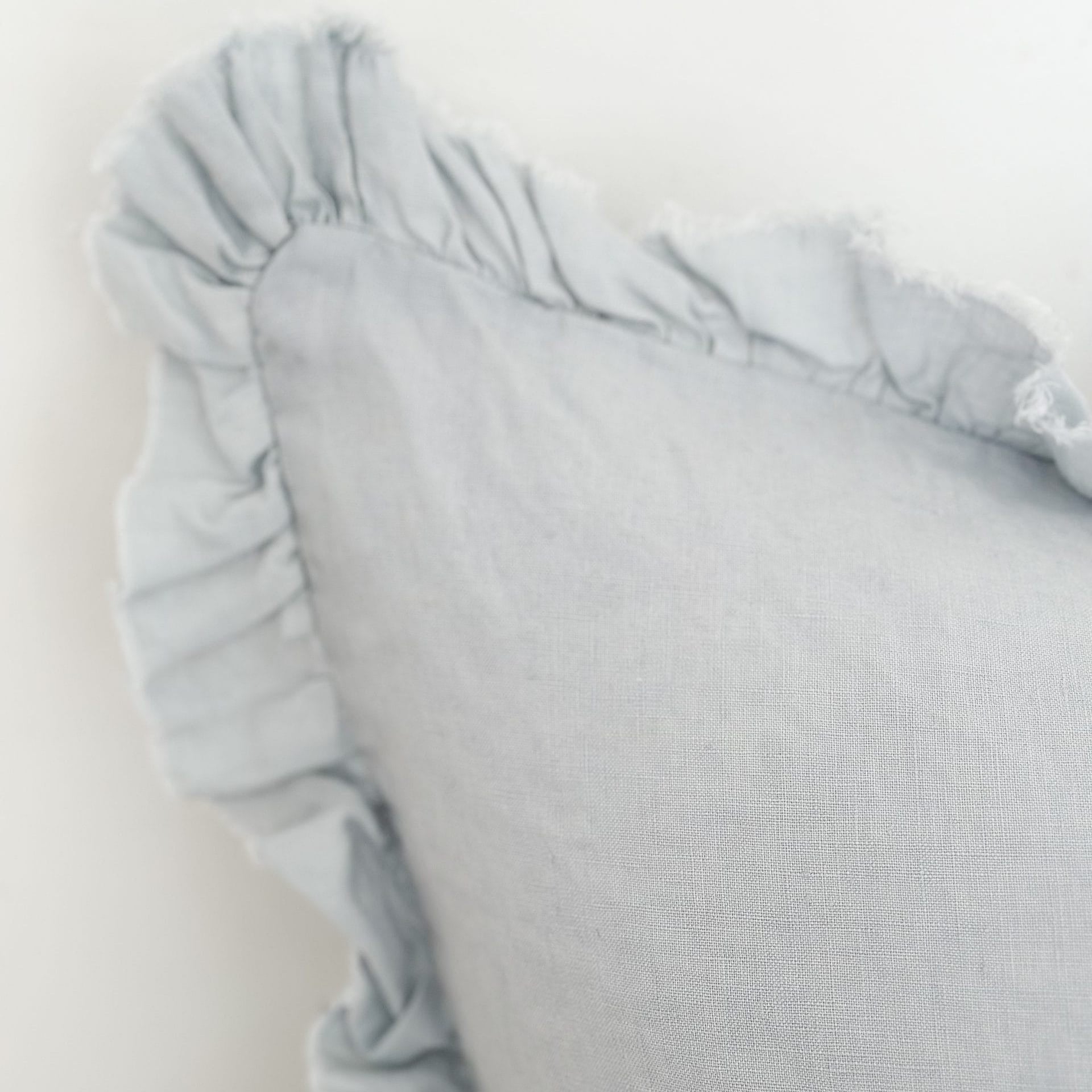 Light blue pillow with ruffled edge on a white background