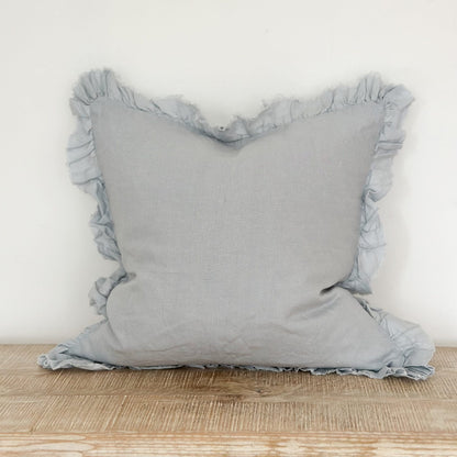pale blue pillow with ruffled edges on a wooden surface