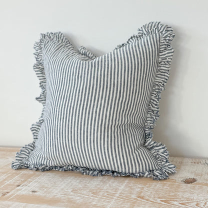 Striped pillow with tassels on a wooden surface and light gray background