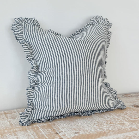 Striped pillow with ruffled edges on a wooden surface
