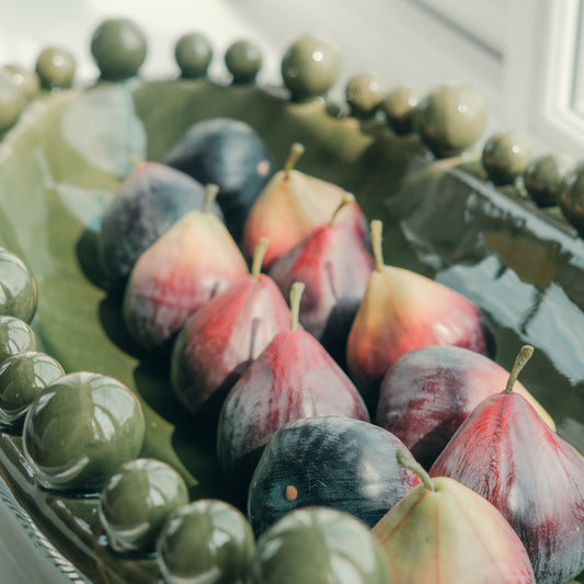 Pair of Faux Decorative Figs on a decorative green plate with a blurred background