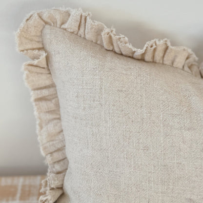 Beige pillow with ruffled edge on a neutral background